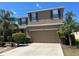 Two-story stucco home with a two-car garage, surrounded by lush tropical landscaping and vibrant blue shutters at 1118 Lauren Manor Loop, Ruskin, FL 33570