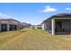 Backyard featuring a screened-in patio, with a well-maintained lawn and other houses and trees in the background at 11831 Thicket Wood Dr, Riverview, FL 33579