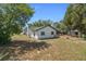 Backyard view of home with white siding, mature trees, and a covered patio at 12493 Fish Cove Dr, Spring Hill, FL 34609