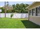 Fenced backyard featuring green grass, a gate, and mature trees, creating a peaceful and private outdoor space at 12606 Rain Forest St, Temple Terrace, FL 33617