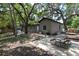 Wide shot of the backyard with mature trees, fenced yard, patio and outdoor seating at 1310 Hilton Pl, Tampa, FL 33604