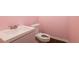 A clean and cozy half-bathroom featuring a modern sink vanity and a toilet, all set against a charming pink backdrop at 1310 Hilton Pl, Tampa, FL 33604