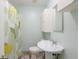 A bright bathroom featuring a pedestal sink, shower with yellow and green floral curtain and clean white fixtures at 1310 Hilton Pl, Tampa, FL 33604