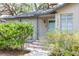 Welcoming front porch with a quaint blue door and decorative landscaping at 1310 Hilton Pl, Tampa, FL 33604
