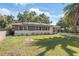 Charming single-story home featuring solar panels, a well-maintained lawn, and lovely mature trees at 1341 Sandy Ln, Clearwater, FL 33755