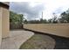 The backyard featuring a block wall, mulched landscaping, and a brick paver patio at 13703 Sweetwater Cove Pl, Tampa, FL 33613