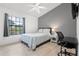 Cozy bedroom with a ceiling fan, window view, desk, and calming gray accent wall at 16504 Lake Brigadoon Cir, Tampa, FL 33618