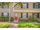 Townhouse with a bright red door, dark shutters, and well-maintained landscaping at 16504 Lake Brigadoon Cir, Tampa, FL 33618