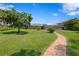 Large backyard with a lush green lawn, mature trees, and a screened-in enclosure visible from the brick path at 19815 Sea Rider Way, Lutz, FL 33559
