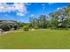Expansive backyard with a winding brick path, manicured landscaping, lush green lawn, and tall trees in background at 19815 Sea Rider Way, Lutz, FL 33559