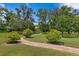 Spacious backyard with a winding brick path and manicured landscaping, surrounded by tall trees at 19815 Sea Rider Way, Lutz, FL 33559