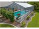 Aerial view of screened-in pool with lounging space, complemented by vibrant landscaping and decorative statues at 19815 Sea Rider Way, Lutz, FL 33559