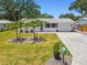 Inviting home with a well-maintained lawn, brick driveway, complemented by mature palm trees at 2004 Yale Ave, Dunedin, FL 34698