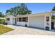 Well-maintained single-story home featuring a garage, decorative shutters, potted plants, and paved driveway at 2004 Yale Ave, Dunedin, FL 34698