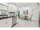 Bright kitchen with stainless steel dishwasher, dining area, and a sliding glass door to the sunroom at 2004 Yale Ave, Dunedin, FL 34698