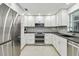 Well-lit kitchen featuring stainless steel appliances, bright white cabinetry, and ample counter space at 2004 Yale Ave, Dunedin, FL 34698