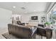 Bright living room featuring sleek couches, decorative console, large windows, and dining area view at 2004 Yale Ave, Dunedin, FL 34698