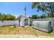 Well-maintained backyard shed with double doors, complemented by a greenhouse and a manicured lawn at 2004 Yale Ave, Dunedin, FL 34698