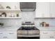Close up of kitchen features stainless steel oven, open shelves, marble countertops, and a gray hood at 2718 N 21St St, Tampa, FL 33605