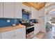 Close-up of kitchen featuring blue backsplash, stainless steel appliances, butcher block countertops, and white cabinets at 300 10Th Ave, Indian Rocks Beach, FL 33785