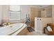 Bright bathroom featuring a large soaking tub, separate glass shower, and tile flooring at 3227 Watermark Dr, Wesley Chapel, FL 33544