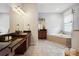 Spacious bathroom featuring dual sinks, dark wood cabinets, a large soaking tub, and tiled floors at 3227 Watermark Dr, Wesley Chapel, FL 33544