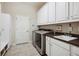 Bright laundry room featuring modern washer and dryer, white cabinetry, tile flooring, and convenient sink area at 3227 Watermark Dr, Wesley Chapel, FL 33544
