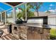 Outdoor grill and cooking area with counter, brick surround, and shade at 3227 Watermark Dr, Wesley Chapel, FL 33544