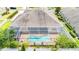 Aerial view of screened pool with unique shape, brick deck, and white fence offering privacy at 3227 Watermark Dr, Wesley Chapel, FL 33544