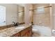 Well-lit bathroom with granite counters, a bathtub with shower, and neutral tile flooring at 3300 Stonegate Falls Dr, Land O Lakes, FL 34638