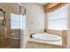 A luxurious soaking tub sits beneath a window, complemented by a glass-enclosed shower at 3300 Stonegate Falls Dr, Land O Lakes, FL 34638