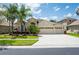 Beautiful home featuring a large driveway, three-car garage, and lush landscaping with palm trees at 3300 Stonegate Falls Dr, Land O Lakes, FL 34638