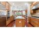 Open kitchen features stainless steel appliances, a central island, warm wood cabinets, and seamless flow into the living area at 3300 Stonegate Falls Dr, Land O Lakes, FL 34638