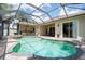 Inviting screened pool and spa featuring clear water, outdoor kitchen, covered lanai, and lush landscaping at 3300 Stonegate Falls Dr, Land O Lakes, FL 34638