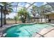 Inviting screened pool and spa featuring clear water, and an outdoor kitchen, surrounded by palm trees at 3300 Stonegate Falls Dr, Land O Lakes, FL 34638