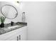 Updated bathroom vanity with a round mirror and granite countertop provides a luxurious feel at 3402 W Clifton St, Tampa, FL 33614