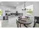 Modern dining area with stylish light fixture, table, and kitchen with stainless steel appliances at 3402 W Clifton St, Tampa, FL 33614