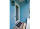 Bright blue front entrance to the house with a white door, textured wall, and lantern style light fixture at 3402 W Clifton St, Tampa, FL 33614