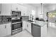 Open concept kitchen features stainless steel appliances and a view into the dining and living areas at 3402 W Clifton St, Tampa, FL 33614