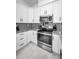 Well-lit kitchen features stainless steel appliances, contemporary backsplash and sleek white cabinetry at 3402 W Clifton St, Tampa, FL 33614
