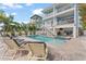 Outdoor oasis featuring a pristine pool, spa, travertine patio, and views of lush tropical foliage at 371 12Th Ave, Indian Rocks Beach, FL 33785