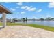 Brick patio with a well-manicured lawn and waterfront views with canal under a partly cloudy sky at 4331 13Th Ne Way, St Petersburg, FL 33703