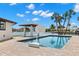 Beautiful pool with a brick patio, home, and canal in the background with a basketball hoop under a partly cloudy sky at 4331 13Th Ne Way, St Petersburg, FL 33703