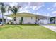Charming manufactured home featuring a well-maintained lawn, carport, and lush palm trees at 5721 Apache St, Zephyrhills, FL 33542