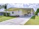 Inviting yellow home featuring a covered carport and lush landscaping at 5721 Apache St, Zephyrhills, FL 33542