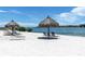 Secluded beach with multiple lounge chairs and tiki umbrellas offering stunning ocean views at 6085 Bahia Del Mar Blvd # 106, St Petersburg, FL 33715