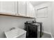 Modern laundry room with black washer and dryer, upper cabinets, and a utility sink for added convenience at 6121 33Rd N Ave, St Petersburg, FL 33710