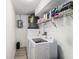 Well-lit laundry room equipped with a washer, dryer, storage shelf, and a water heater system at 6121 Fjord Way, New Port Richey, FL 34652