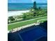 View from condo overlooking the pool, lawn, landscaping, and beach at 7150 Sunset Way # 405, St Pete Beach, FL 33706