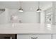 Close-up of a kitchen island featuring a sleek countertop, modern pendant lighting, and cabinetry at 7232 Sutton Ln, Sarasota, FL 34240